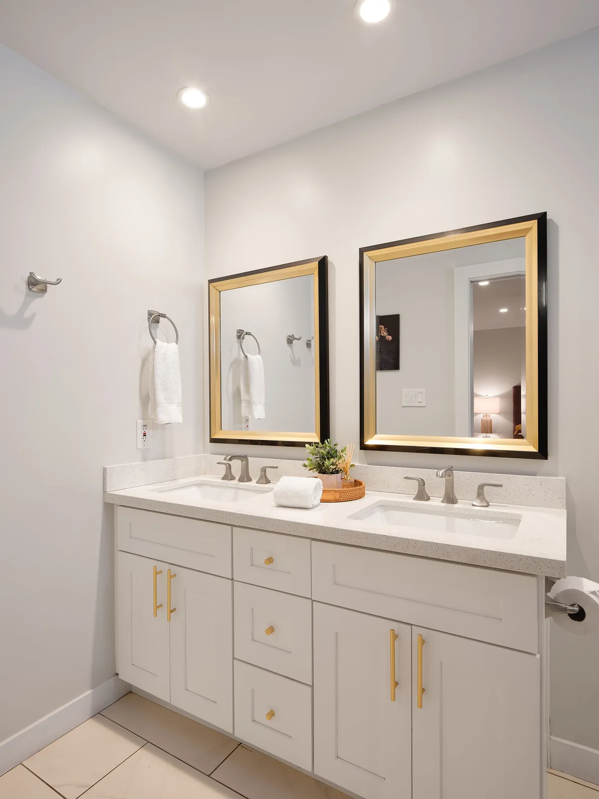 A bright bathroom with a double vanity, gold-framed mirrors, and neatly arranged towels, creating a fresh and inviting space for morning and evening routines. The atmosphere is both stylish and practical, aligning with the property's upscale appeal.