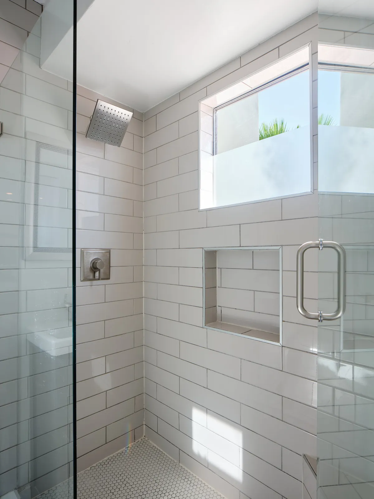 A modern bathroom featuring a glass shower enclosure, geometric tiles, and abundant natural light. The sleek fixtures and spa-like ambiance offer a touch of everyday luxury, ideal for relaxing self-care routines.