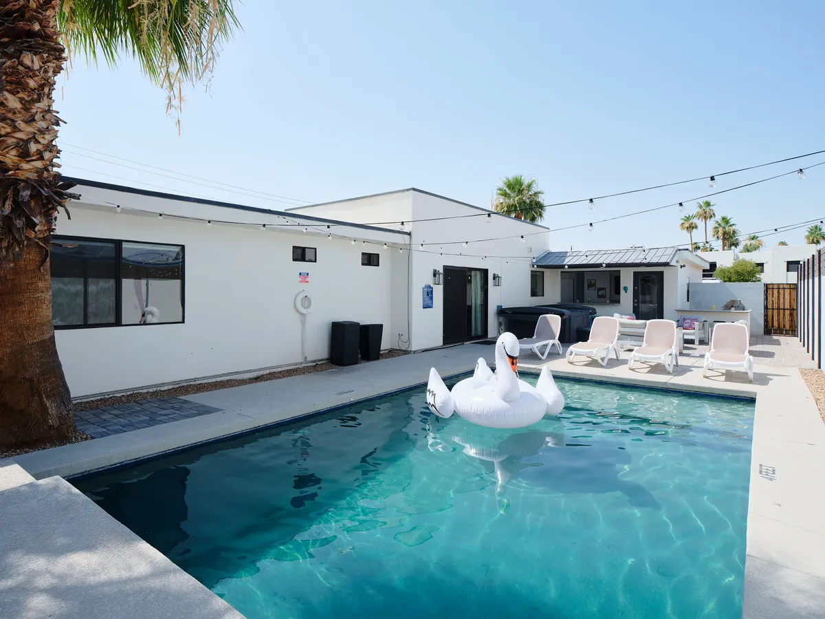 A playful backyard scene shows a sparkling swimming pool with an inflatable swan, surrounded by lounge chairs and palm trees. The inviting area radiates fun and relaxation, perfect for unwinding together after a day of adventure.