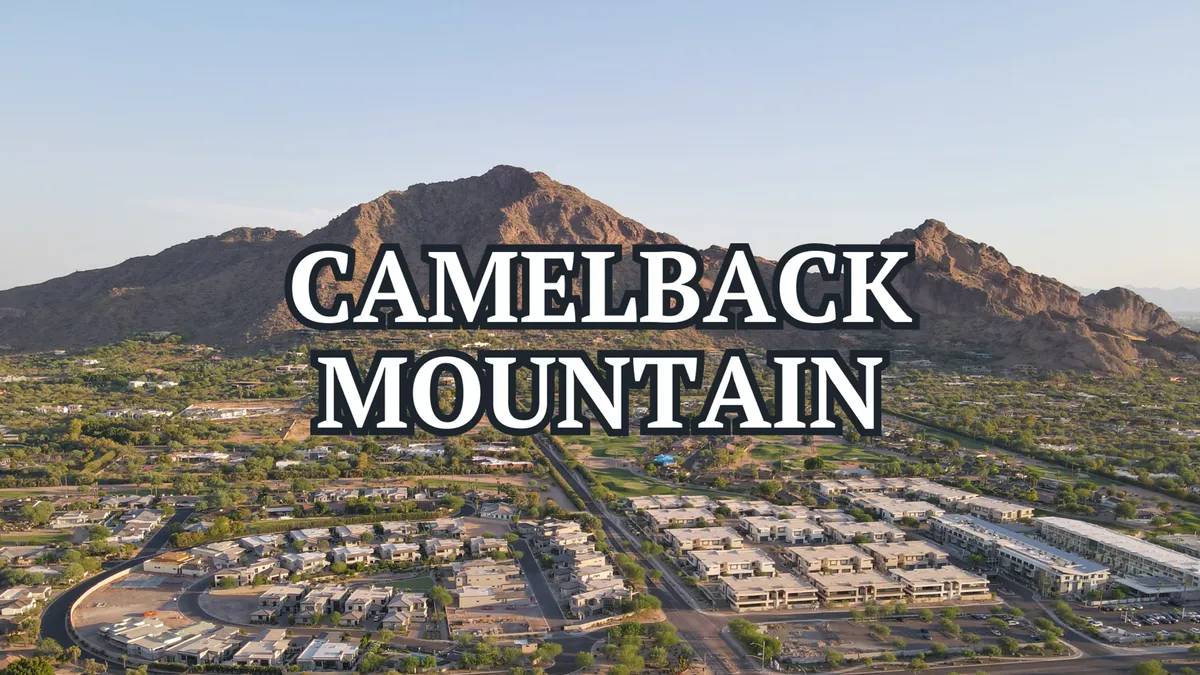 A sweeping view of Camelback Mountain dominating the skyline, with green spaces and suburban development in the foreground. The landscape is tranquil, highlighting the mountain's popularity for hiking and outdoor adventures.