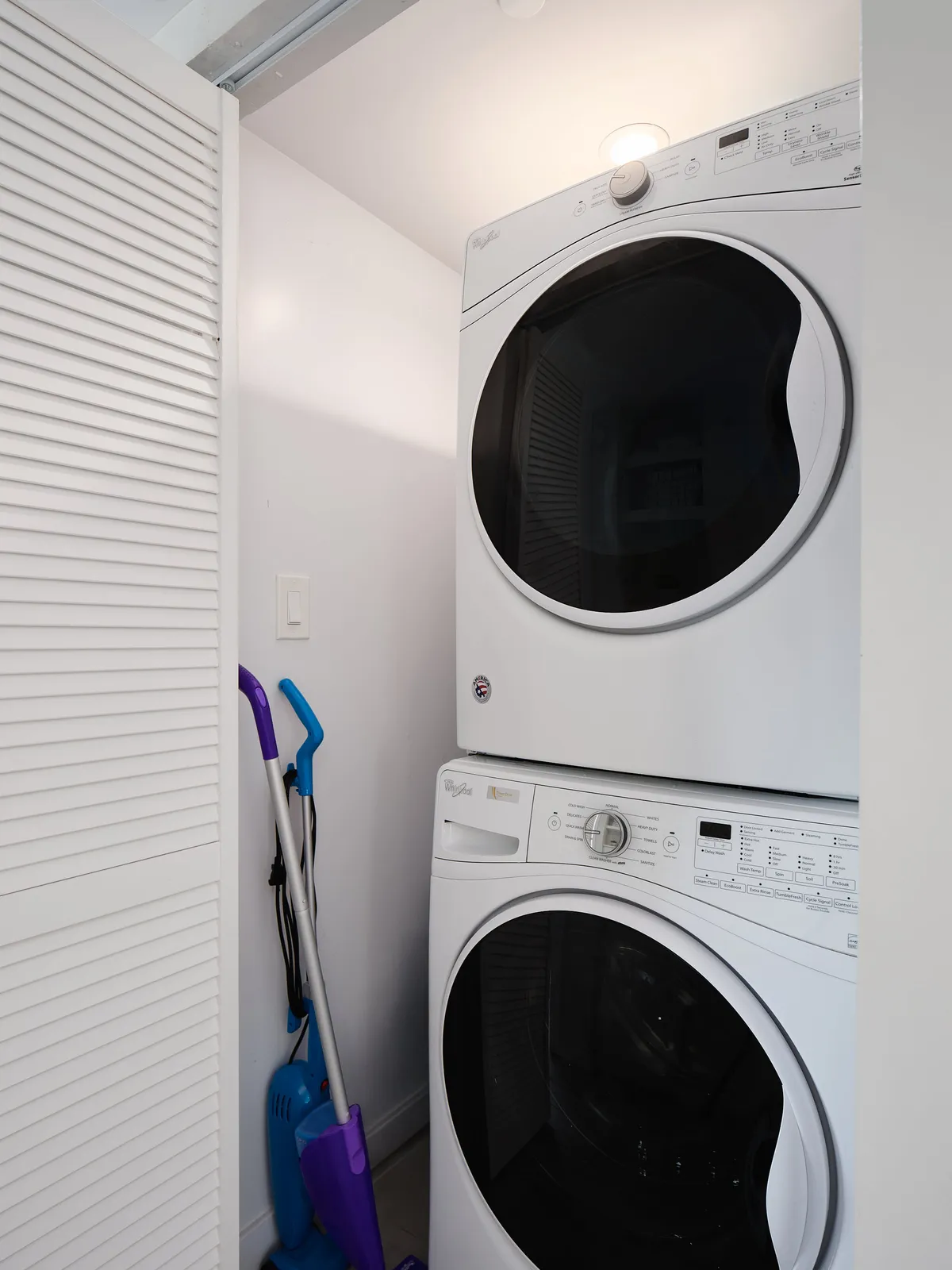 A stacked washer and dryer with organized cleaning supplies in a dedicated laundry space, emphasizing order and cleanliness throughout the home.